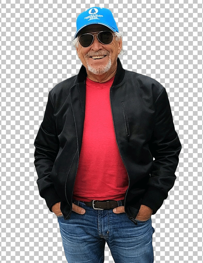 Jimmy Buffett Standing and wearing a red baseball cap, black jacket, and blue jeans.