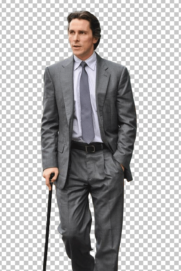 Christian Bale is in a gray suit, holding a stick.