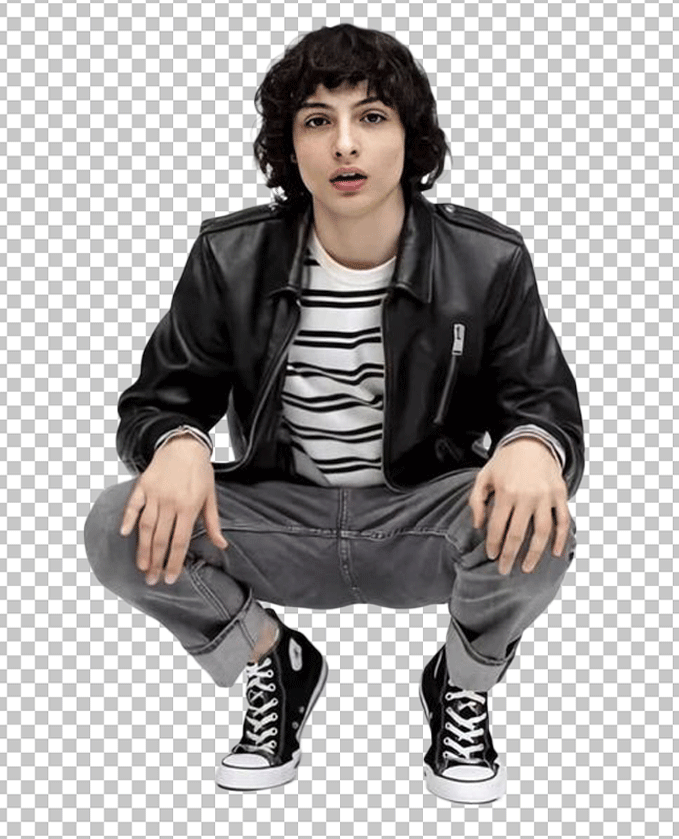 Finn Wolfhard is sitting on his knees and wearing a black leather jacket.