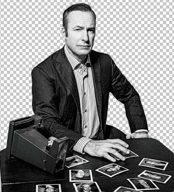 Black and white image of Jimmy McGill sitting at a table with a stack of photographs in front of him.