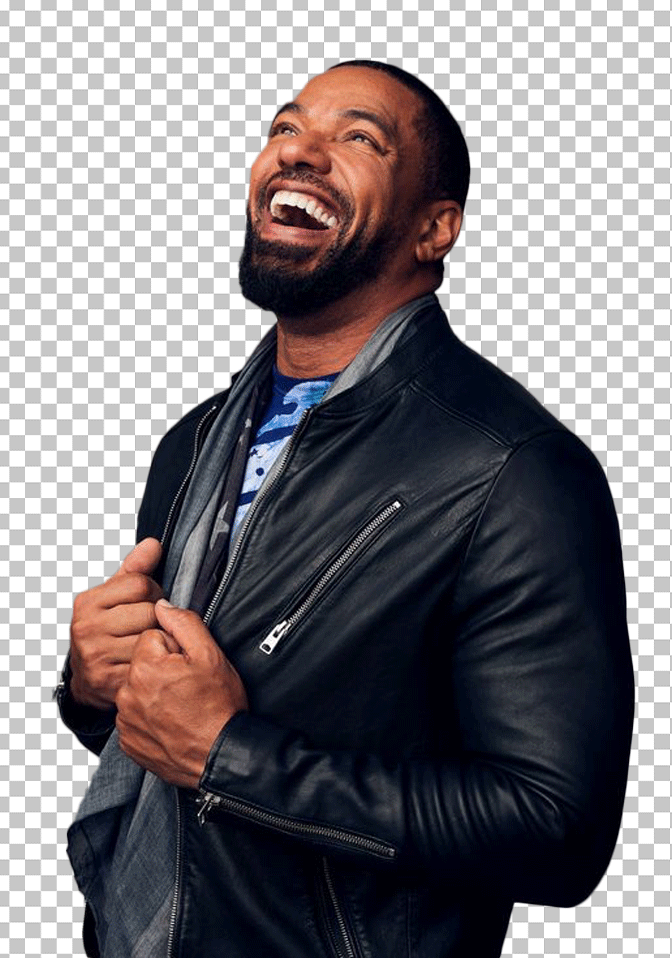 Laz Alonso is wearing a black leather jacket and a beard, laughing.