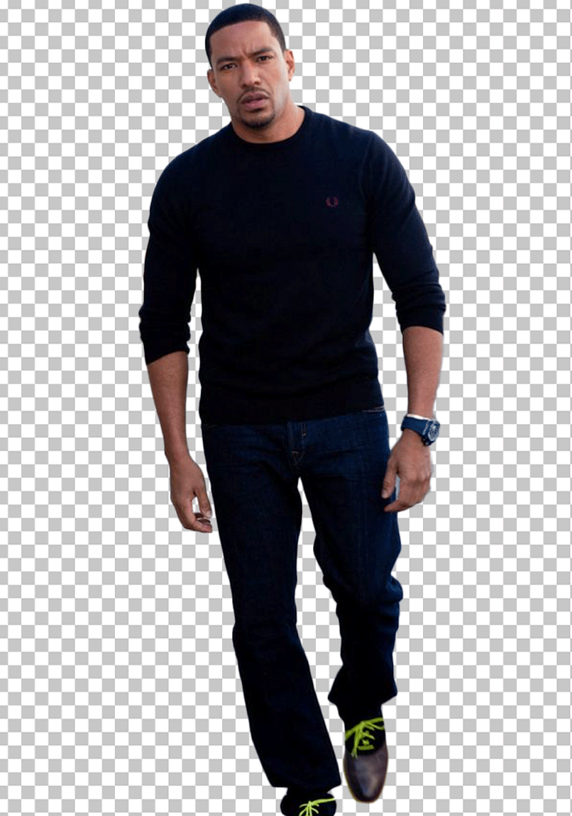 Laz Alonso is wearing a black sweater and blue jeans and walking.