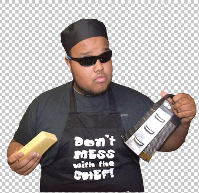 Chunkz is making food, holding a piece of cheese in one hand and a steel Grater in the other.