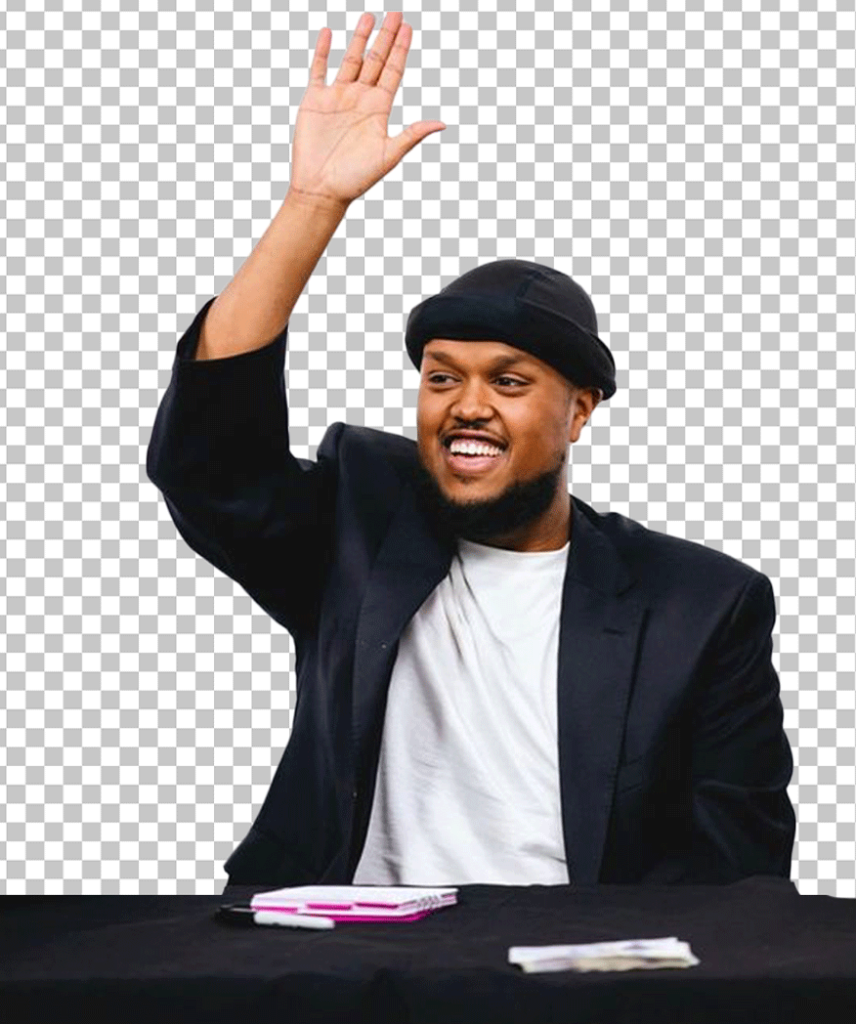 Chunkz is sitting at a table with his hands raised in the air