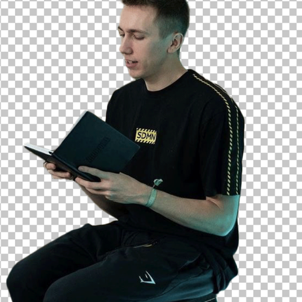 Simon Minter is sitting on a stool, reading a book PNG Image