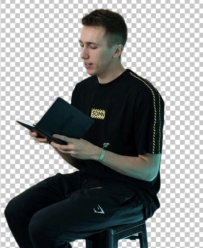 Simon Minter is sitting on a stool, reading a book PNG Image